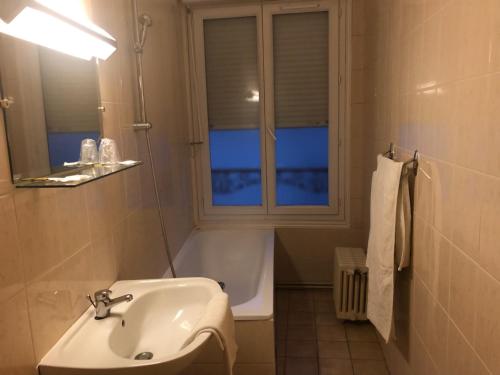 łazienka z umywalką, wanną i oknem w obiekcie Hôtel des Couronnes Châteaudun w mieście Châteaudun