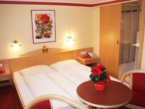 ein Hotelzimmer mit einem Bett und einem Tisch mit Blumen darauf in der Unterkunft Pension Steiner in Mayrhofen