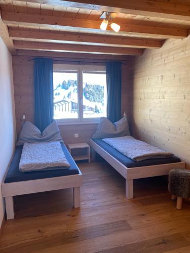two beds in a room with a window at Bim See in Bettmeralp