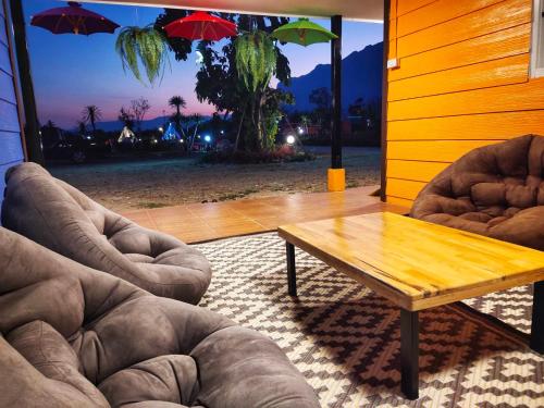 a living room with two chairs and a wooden table at Ban Thung Talay Mok Chiangdao in Chiang Dao