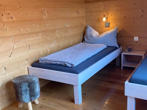 a bed in a room with a wooden wall at Bim See in Bettmeralp