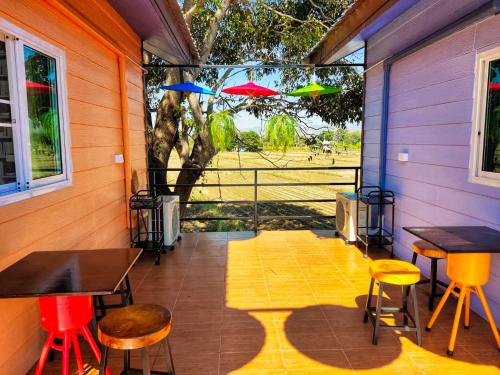 a screened porch with tables and chairs and umbrellas at Ban Thung Talay Mok Chiangdao in Chiang Dao