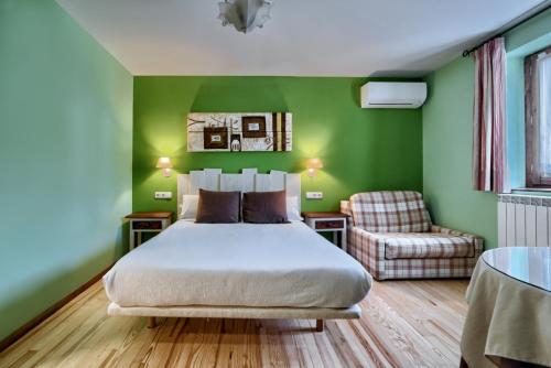 1 dormitorio con paredes verdes, 1 cama y 1 silla en Hostal Almadiero, en Burgui