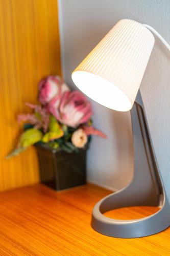 a table with a lamp and a vase of flowers at Fenix in Pathum Thani