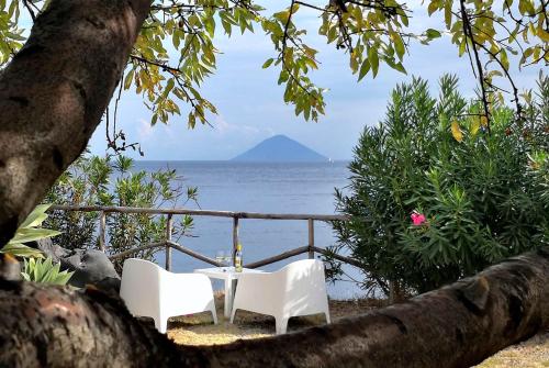 una mesa y dos sillas sentadas junto al océano en Le case di Eolo - Santa Marina Salina, en Santa Marina Salina