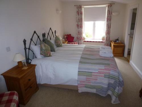 a bedroom with a large white bed and a window at The Manor House in Puncknowle