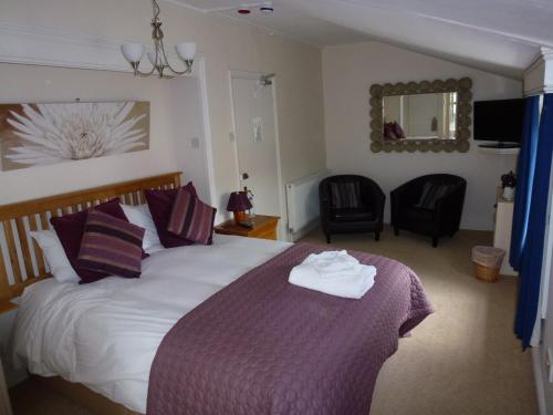 a bedroom with a large bed and two chairs at The Manor House in Puncknowle