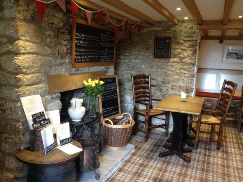 a restaurant with a table and chairs and a stone wall at The Manor House in Puncknowle