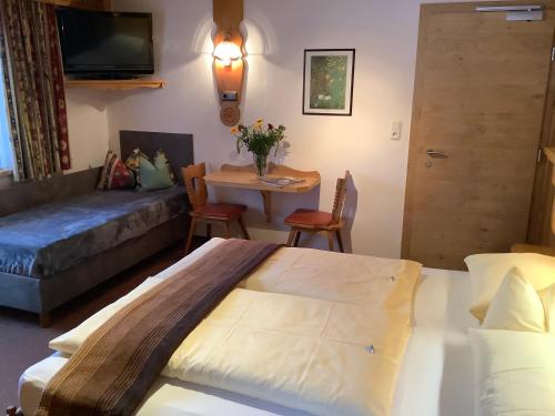 a room with a bed and a couch and a table at Anja's Schönblick - Bed & Breakfast in Gerlos