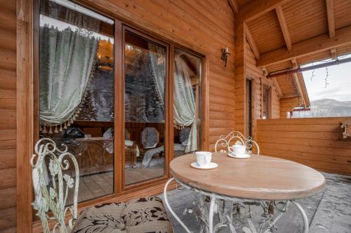 einen Tisch und Stühle in einem Zimmer mit einem großen Fenster in der Unterkunft Villa Ladna Tatariv Bukovel in Tatariw