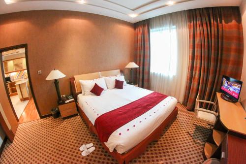 a hotel room with a large bed and a television at City Center Hotel in Manama