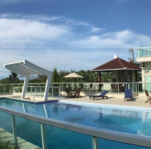 einen Pool in einem Resort mit Stühlen und Sonnenschirmen in der Unterkunft Maravilhoso apartamento novo em condomínio clube. in Penha