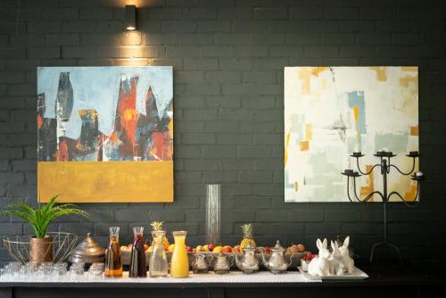 un tavolo con cibo e dipinti su un muro di Ruby Rose a Riebeek-Wes
