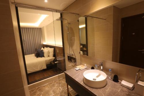 a bathroom with a sink and a bed and a mirror at FLC Grand Hotel Quy Nhon in Quy Nhon