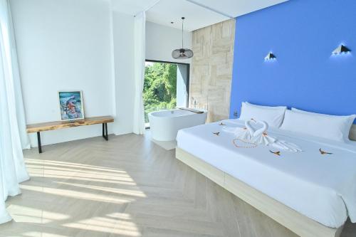 sypialnia z białym łóżkiem i niebieską ścianą w obiekcie Chomdao Maikhao w mieście Ban Bo Sai Klang