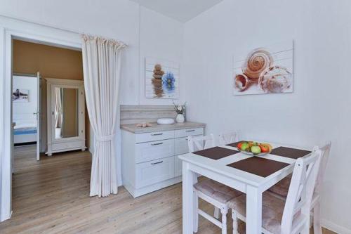 a kitchen with a table and a white table and chairs at App-6-mit-Suedbalkon-in-strandnaher-Lage-Baederstil-Villa-in-Wenningstedt-Sylt in Wenningstedt