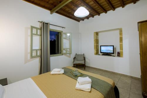 a bedroom with a bed and a tv and windows at Basilikos traditional house, 10' from Falasarna in Kissamos