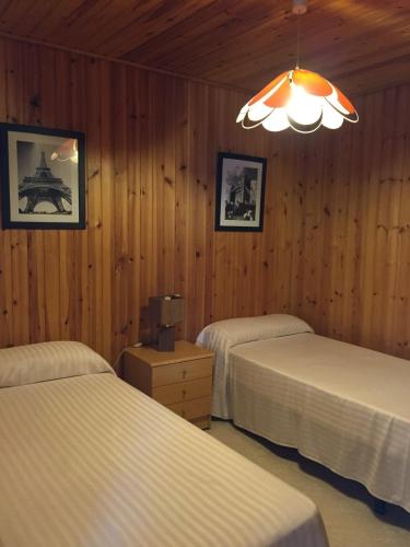 a bedroom with two beds and a chandelier at Bungalow 1 - Playa Arnela in Carballo