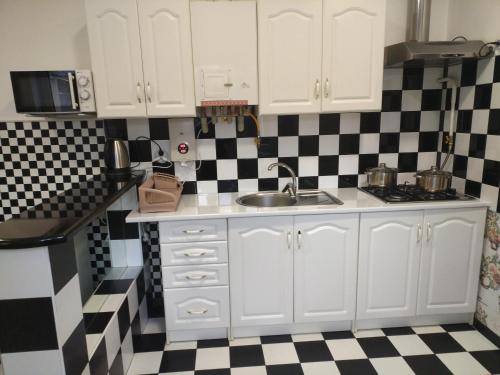a kitchen with white cabinets and a black and white checkered floor at Private House in Berehove