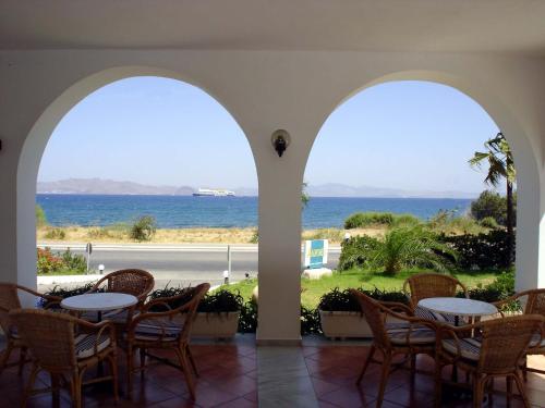a patio with tables and chairs and the ocean at Andromeda Hotel Apartments in Kos Town