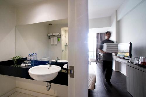 a man walking through a bathroom with a sink at Grand Zuri Cikarang Jababeka in Cikarang