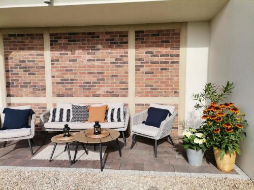 a patio with chairs and tables and a brick wall at Tulipanowy Gościniec in Jantar