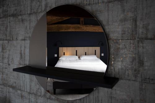 a bedroom with a bed in a round mirror at Hotel - Restaurant Les 3 Piliers in Le Boupère