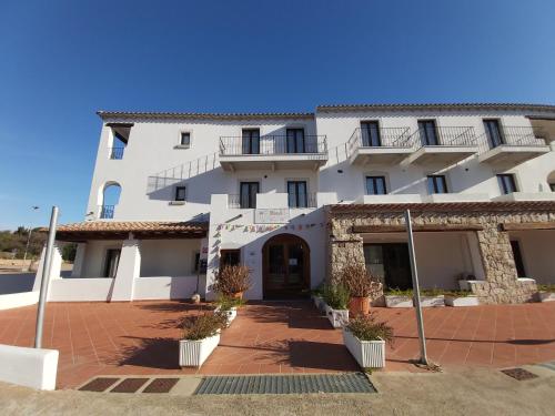 a large white building with a courtyard in front of it at Hotel il Faro di Molara in Porto San Paolo