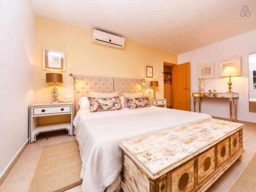 - une chambre avec un grand lit et une poitrine en bois à l'extrémité dans l'établissement VILLA JARAMA Elegante chalet cerca de la playa, à Binibeca