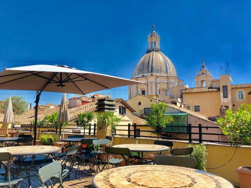 a patio with tables and chairs and an umbrella at Navona Residenza de Charme in Rome