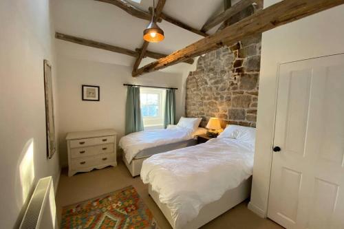 a bedroom with two beds and a stone wall at How Stean Cottage, a gorgeous home in Nidderdale in Harrogate