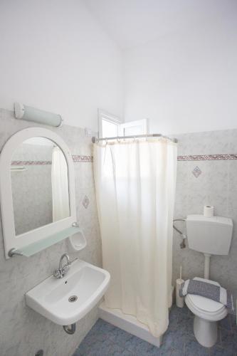 a bathroom with a sink and a toilet and a mirror at Louiza Hotel in Parikia