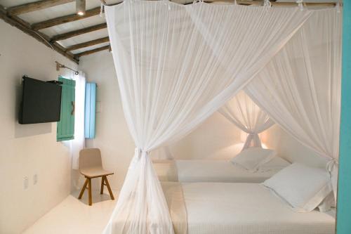 um quarto com uma cama de dossel branca com cortinas em Anbê Hospedaria em Arraial d'Ajuda