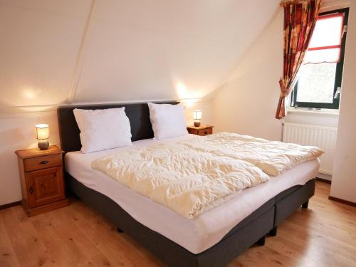 a bedroom with a bed with white sheets and a window at Buitenplaats 5-p in Callantsoog