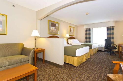 Habitación de hotel con 2 camas y sofá en Days Inn & Suites by Wyndham La Crosse-Onalaska, en Onalaska