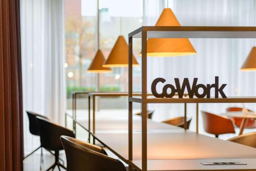 a table with chairs and a company sign on the window at Comwell Aarhus Dolce by Wyndham in Aarhus