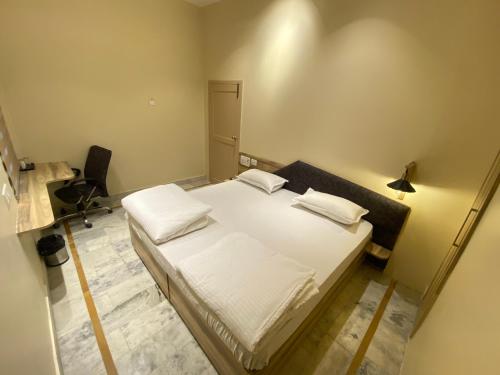 a small room with a bed and a desk at Backpackers Den in Lucknow