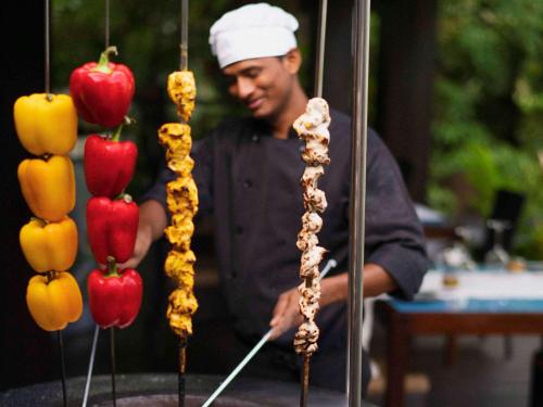 a man in a chefs hat preparing food on a stand at Raffles Seychelles in Baie Sainte Anne