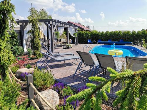 a patio with a table and chairs next to a pool at Tulipanowy Gościniec in Jantar