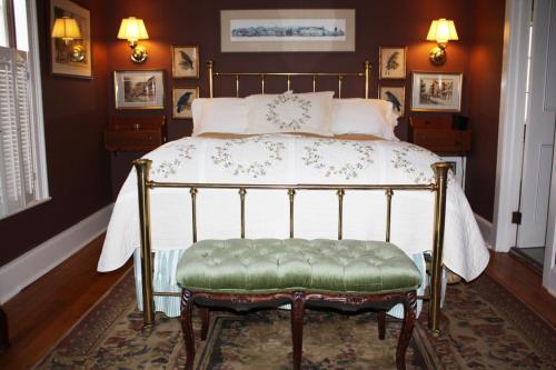 1 cama con banco verde en un dormitorio en The White House Inn, en Cooperstown