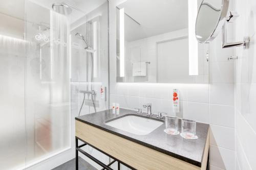 a white bathroom with a sink and a shower at IntercityHotel Wiesbaden in Wiesbaden