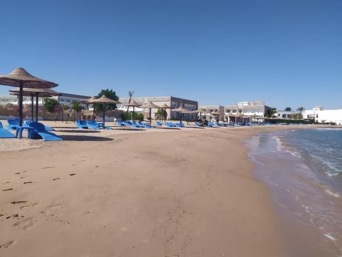 a beach with blue lounge chairs and the ocean at 2nd Cecilia beach resort studio in Hurghada