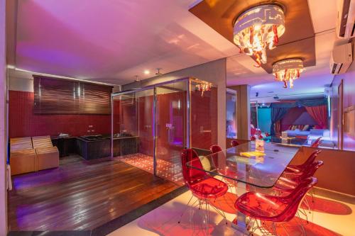 a dining room with a glass table and red chairs at Assahi Motel (Adult Only) in Fortaleza