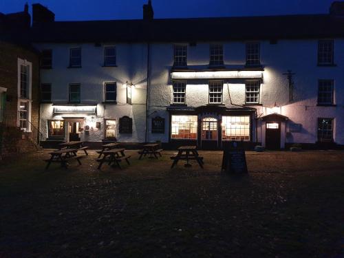 a group of picnic tables in front of a building at night at Black Bull Hotel in Reeth