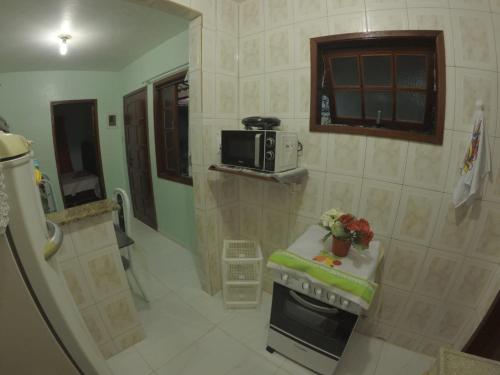 a small kitchen with a stove and a microwave at Casa verde mar in Arraial do Cabo