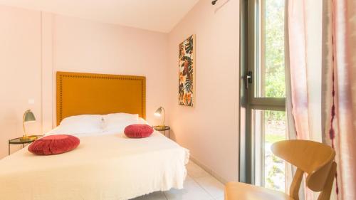 Un dormitorio con una cama con almohadas rojas. en "Le Soleil Levant" avec balcon et parking privé, 2 adultes et 1 enfant, en Sarlat-la-Canéda