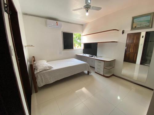um quarto com uma cama, uma secretária e uma televisão em Casa 4/4(Amplos), Cond. fechado com piscina-150m2 em Salvador