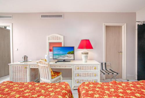 a room with a desk with a computer and a lamp at Karibea Squash Hôtel in Fort-de-France