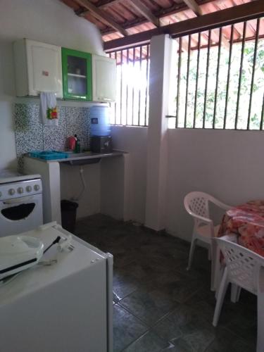 eine Küche mit einem Herd und einem Tisch sowie einige Fenster in der Unterkunft Casa do Mineiro in Nova Viçosa