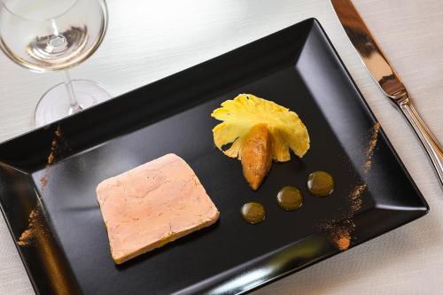 a black plate with a piece of food and a piece of cheese at Hostellerie Schwendi in Kientzheim